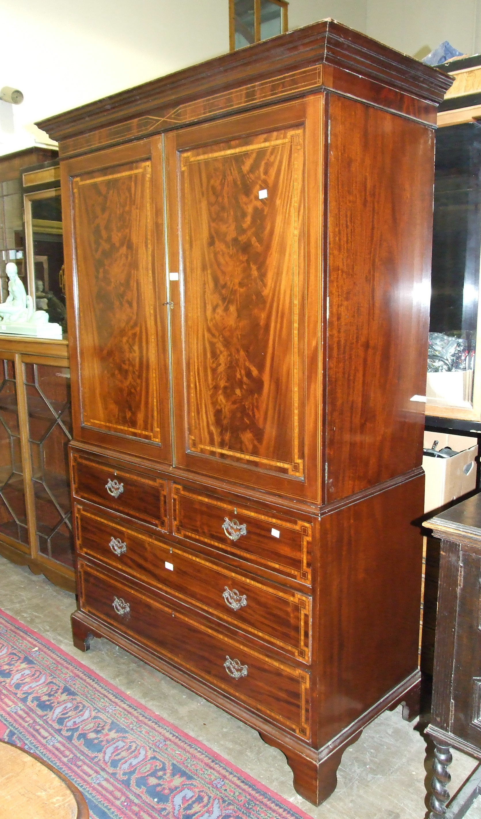 A late-19th century inlaid and cross-banded mahogany linen press, the cornice above a pair of doors,