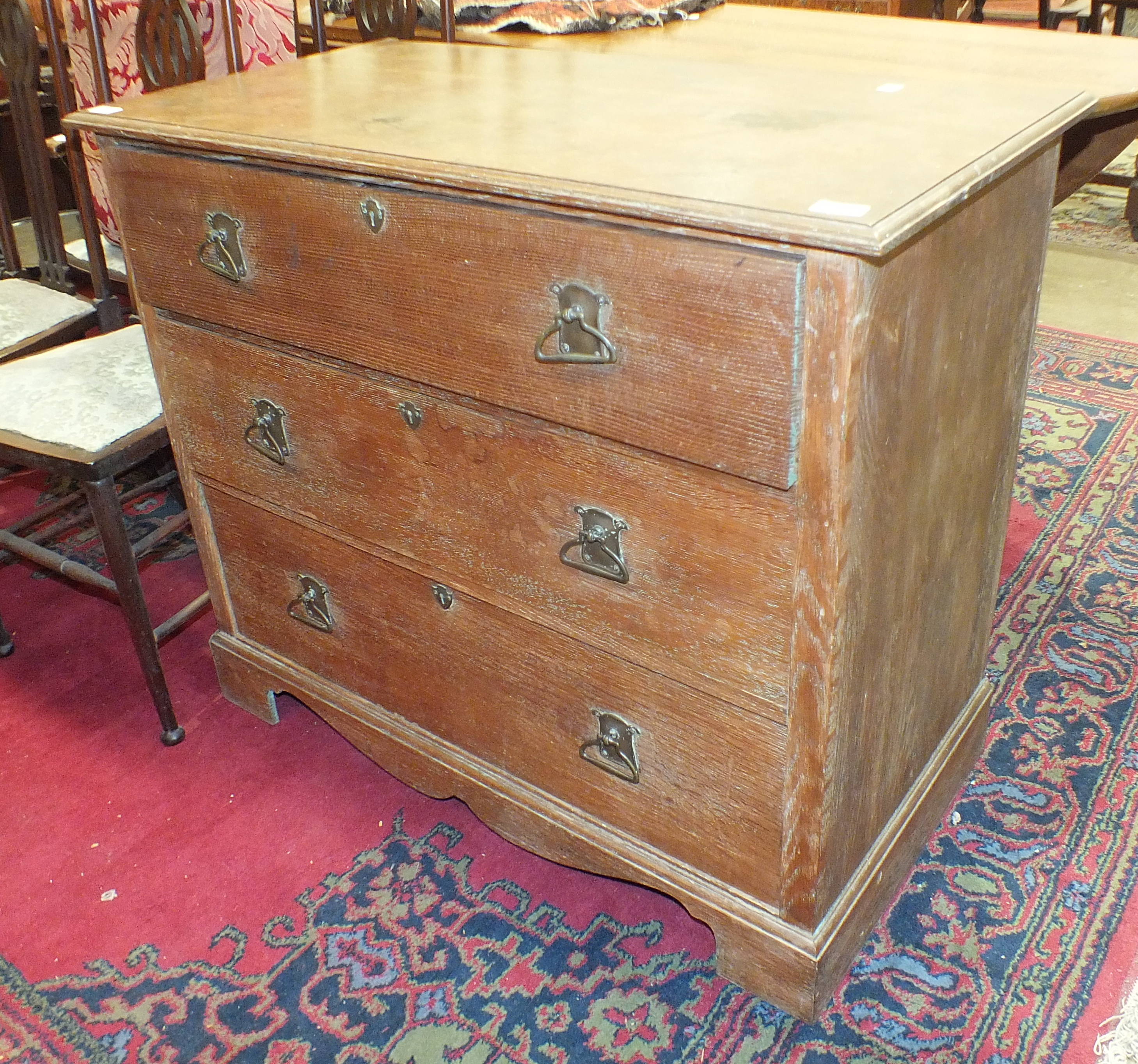 An Edwardian three-drawer oak chest with Art Nouveau brass handles, on bracket feet, 99cm wide.