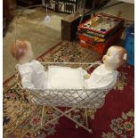 A Victorian wrought iron doll's cot with X-frame, string sides and net arc, 68cm long, 94cm high,