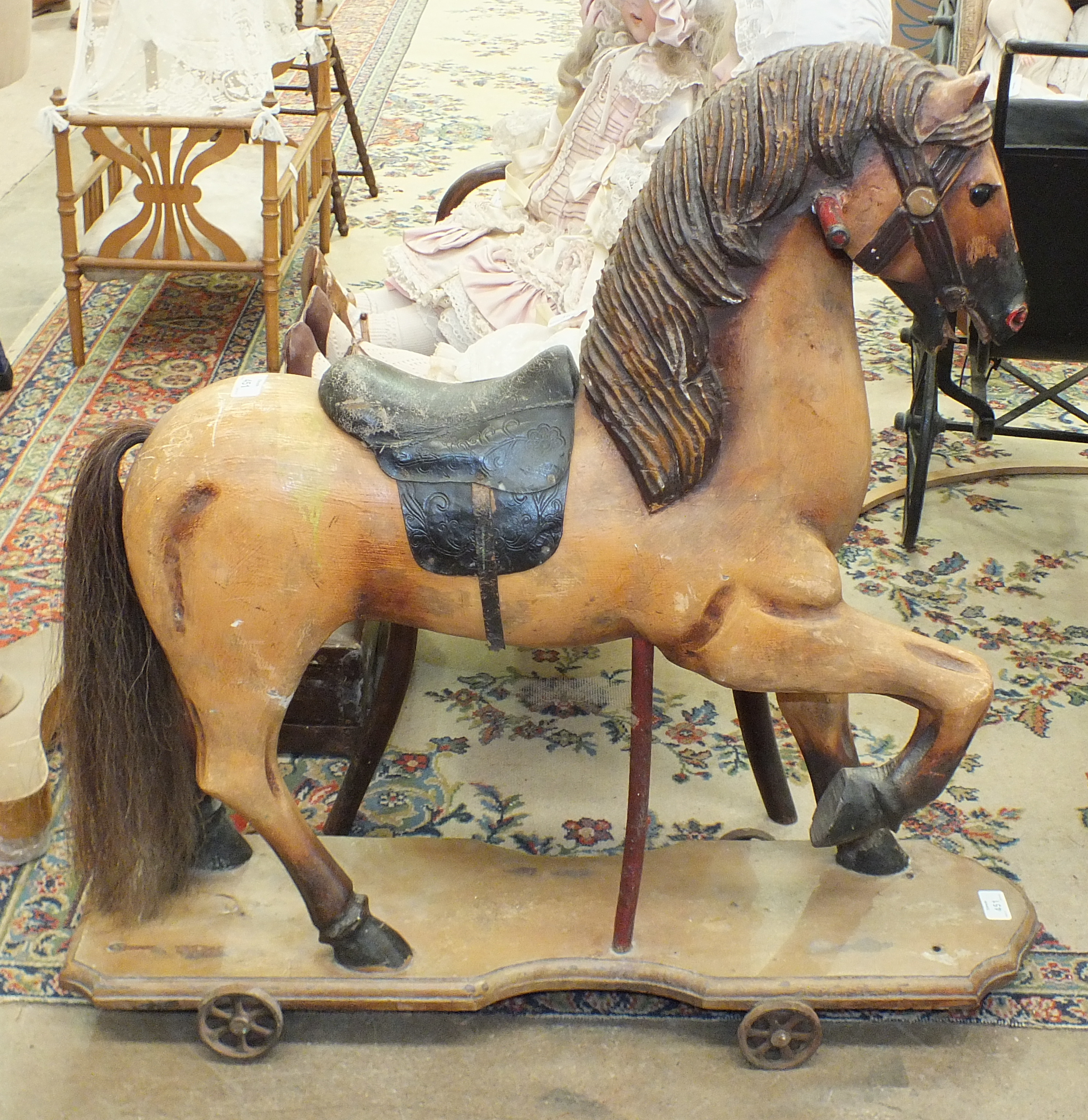 A carved wood push-along horse on cast iron wheels, 77cm high, 81cm long, (no handle).