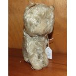 A soft toy seated cat with shaved muzzle, no eyes, felt ears, pink stitched nose and long mohair