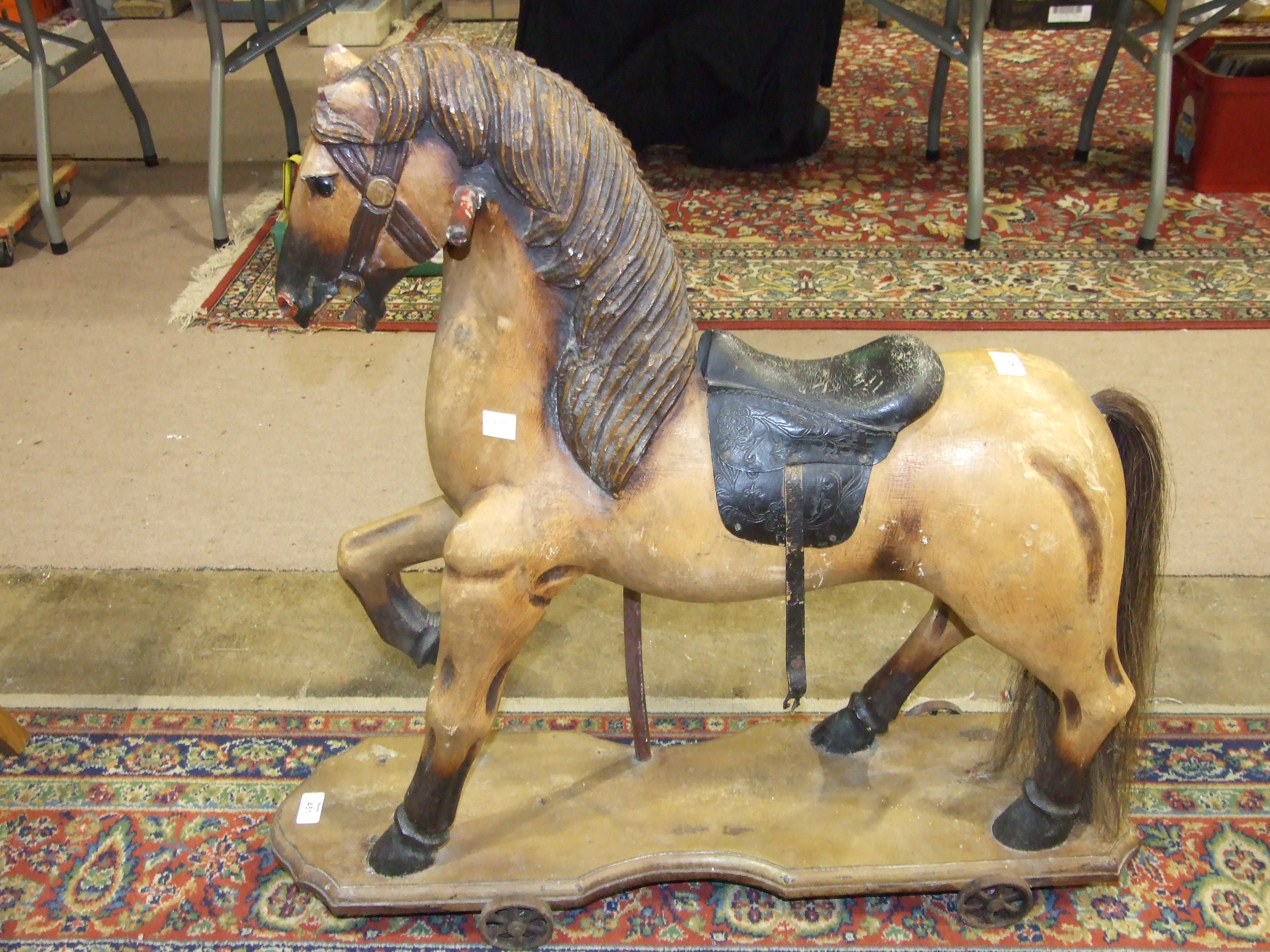A carved wood push-along horse on cast iron wheels, 77cm high, 81cm long, (no handle). - Image 2 of 2