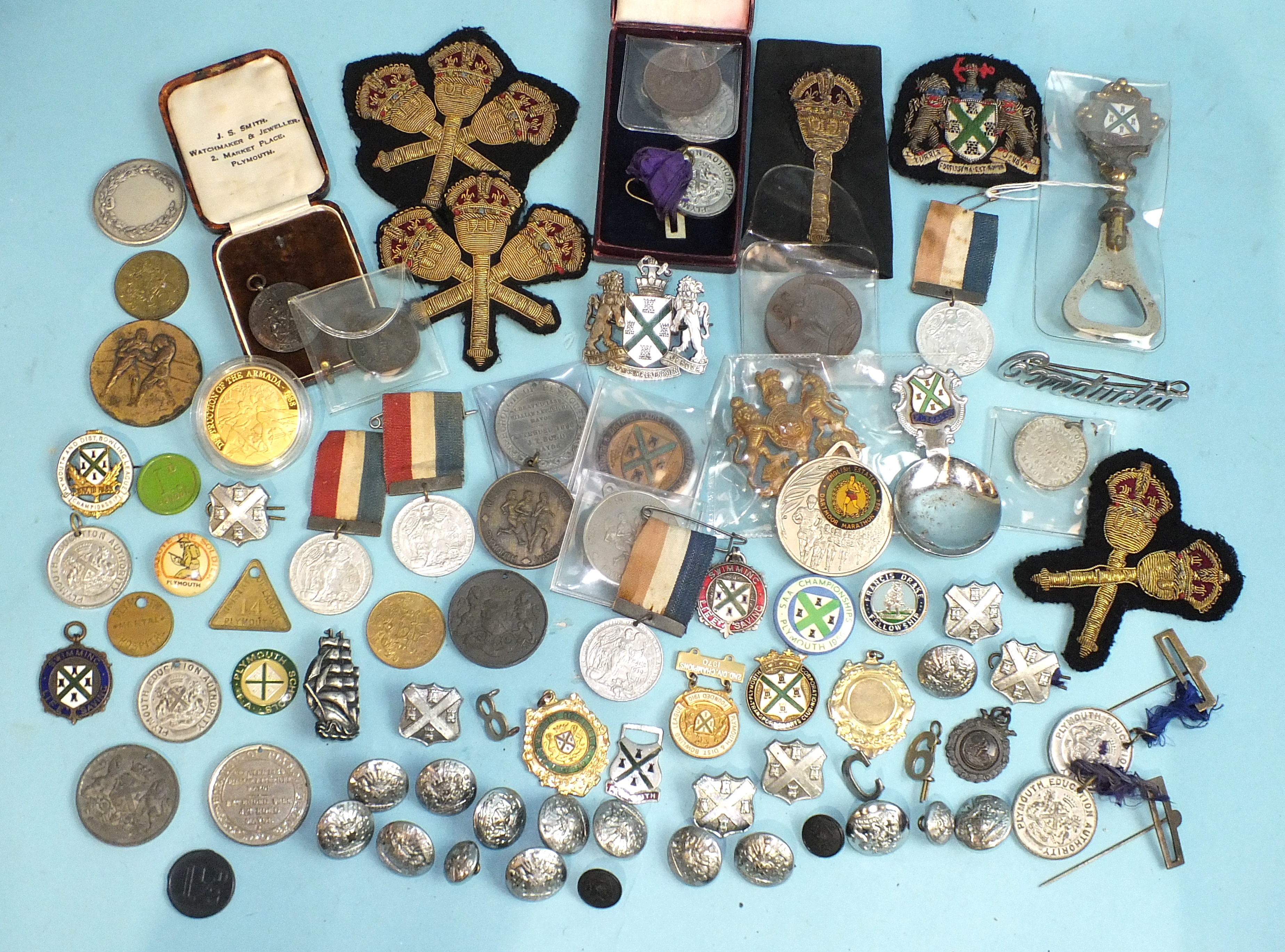 A collection of various metal medallions relating to Plymouth, including school attendance,
