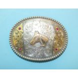 A Tony Lama sterling silver belt buckle decorated with applied yellow metal scroll borders and set