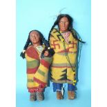 A pair of native American Indian dolls, a brave and squaw with baby in papoose, one with 'Skookum (