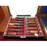 A set of six each horn-handled steak knives and forks, in fitted case.