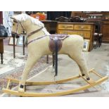 A child's modern corduroy-covered rocking horse with plastic saddle and bridle, 104cm wide.