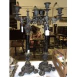 A pair of Victorian cast metal three-branch candelabra, each column supported by putti and triform