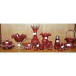 A collection of cranberry glassware, including a basket with frilled rim and white glass handle,