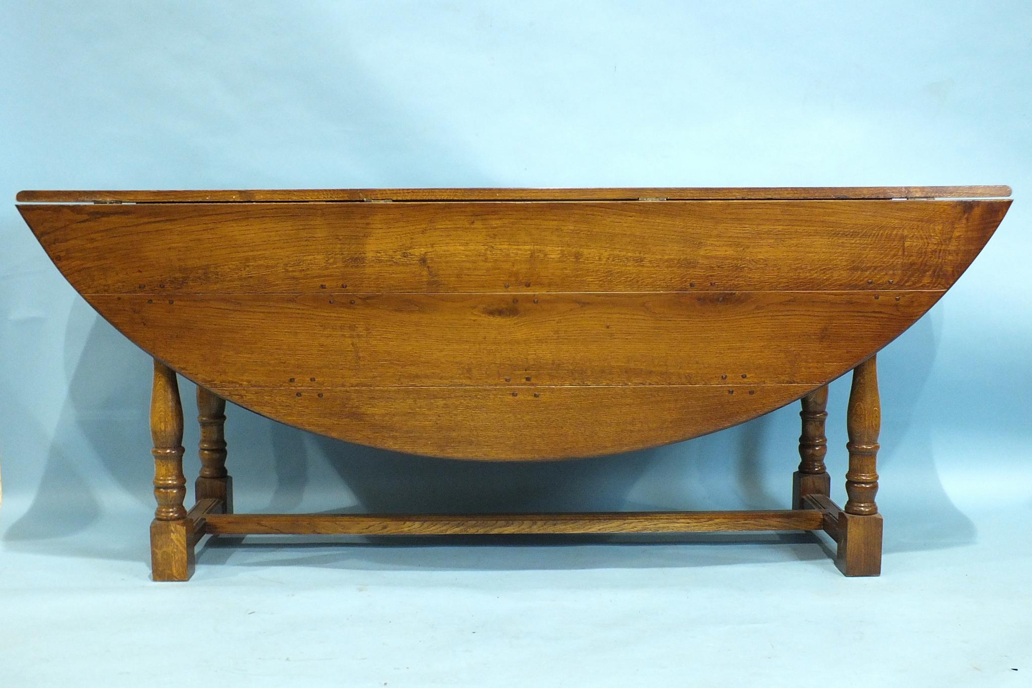 A reproduction elm wake table by Brights of Nettlebed, on turned legs joined by centre stretcher,