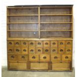A shop or apothecary's pine cabinet of twenty-four small drawers and three drop-down cupboards,