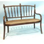 An early-20th century child's Austrian bentwood settee with spindle back and caned seat, with