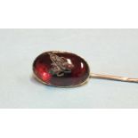 A Victorian stick pin collet-set an oval garnet cabochon, surmounted with a diamond-set fly motif,