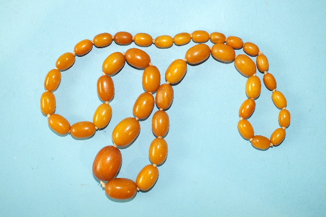 A string of graduated yellow amber oval beads, 67g, largest 28 x 20mm, smallest 11 x 8mm, 79cm