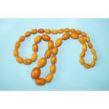 A string of graduated yellow amber oval beads, 67g, largest 28 x 20mm, smallest 11 x 8mm, 79cm