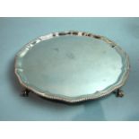 A plain circular salver with gadrooned edge, on claw and ball feet, engraved with crest, London