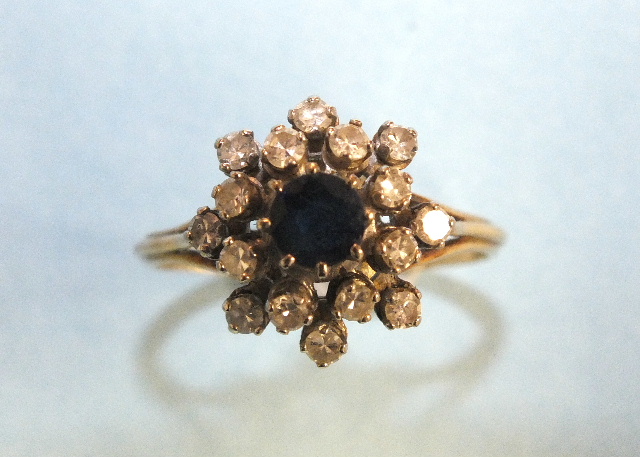 A sapphire and diamond cluster ring set a round-cut sapphire and sixteen 8/8-cut diamonds, in