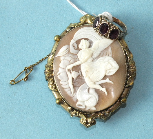 A shell cameo brooch depicting an angel and a three-stone garnet ring, unmarked, (2).