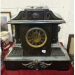 A large black slate striking mantel clock of architectural form, with visible escapement and applied