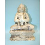 An Asian marble statue of a deity in prayerful attitude, seated on a plinth and carved with a dog,