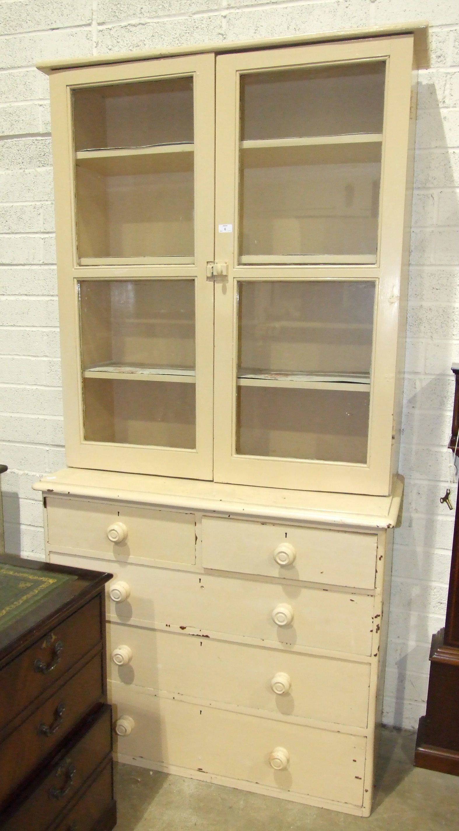 A painted wood bookcase, the glazed top above five drawers, 105cm wide, 215cm high and a painted