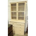 A painted wood bookcase, the glazed top above five drawers, 105cm wide, 215cm high and a painted