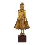 Holzfigur des stehenden Buddha. THAILAND, 20. Jh..Auf einem kleinen Sockel stehend, H 80 cm.