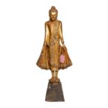 Holzfigur des stehenden Buddha. THAILAND, 20. Jh..Auf einem kleinen Sockel stehend, H 76 cm.