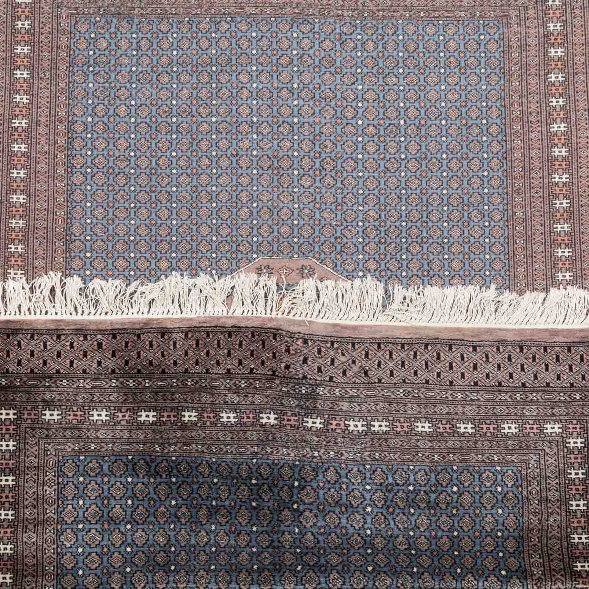 Orientteppich.PAKISTAN, 20. Jh., 187x127 cm.Das stahlblaue Innenfeld ist netzartig überspannt von - Bild 3 aus 4