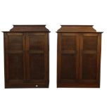 A pair of early 20th C oak side cabinets, the two panelled doors with wooden stud detail, shelved