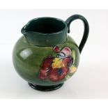 Moorcroft pottery green ground water jug decorated with flowers, paper label and blue mark to