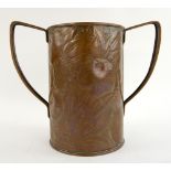 An Arts & Crafts twin handled cup, with hammered decoration of fruit and foliage, unmarked, 22.5