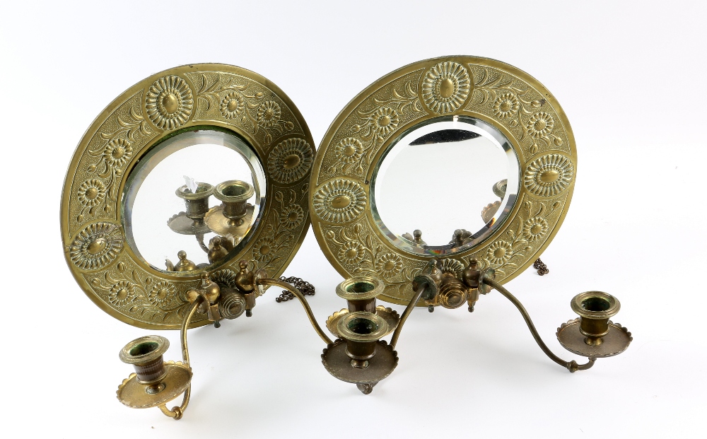 A pair of Ascetic movement brass mirrored candle sconces, the circular frames embossed with floral