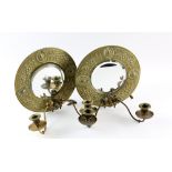 A pair of Ascetic movement brass mirrored candle sconces, the circular frames embossed with floral