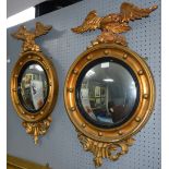 Pair of convex gilt wall mirrors with eagle finials .