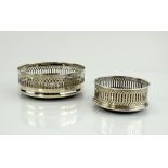 Two silver-mounted bottle coasters, one by Mappin & Webb, 14 cm diam., the second 9 cm diam. (2) .