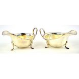 George V pair of silver sauce boats, with scalloped rims and on three feet, 14.5 cm long, 7 oz. (220