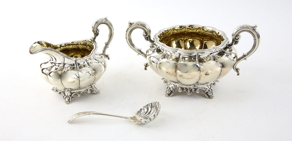 William IV silver cream jug and sugar bowl of lobed form with scroll handles on four shape feet,