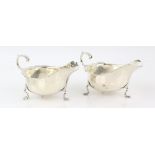 Pair of George V silver sauce boats, with wavy rims on three shaped feet, by Robert Stewart, London,