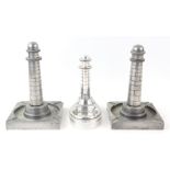 Three novelty aluminium table lighters in the form of lighthouses, tallest pair 19.5 cm .