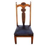 Art Nouveau oak nursing chair with carved floral splat back and studded brown seat, on tapering