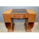 An Art Deco walnut desk the central drawer with scallop edge, further drawers and shaped sides (