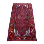 Persian type red ground rug, the border decorated with birds with central medallion, 220cm x 110cm .