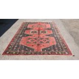 Iranian Caucasian red ground carpet, the centre with three red ground medallions 300cm x 200cm .