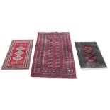 Afghan type red ground rug 160cm x 96cm and two prayer mats, each 93cm x 60cm .