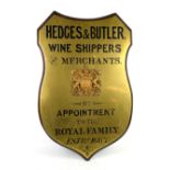 Hedges & Butler wine merchants mahogany and brass shield shaped advertising sign, 94cm x 60cm,.