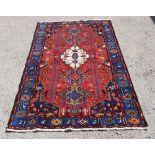 Borchalou red ground rug with a main blue border, the centre with a cream medallion 200cm x 133cm .