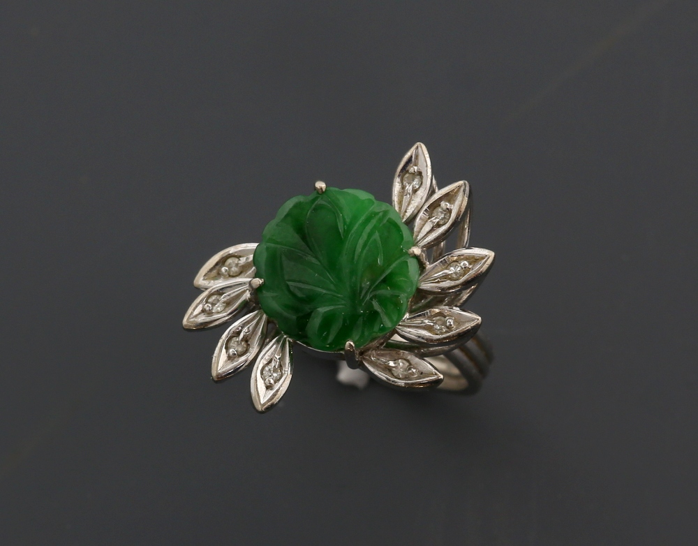 Jade and diamond ring, round floral carved jade panel, surrounded by nine marquise petals set with