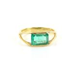 Dress ring set with a stepped cut emerald in plain gold mount, stamped 18 ct, ring size L .