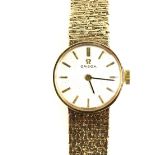 Omega vintage gold ladies watch, round dial with black baton markers, manual wind, on a textured